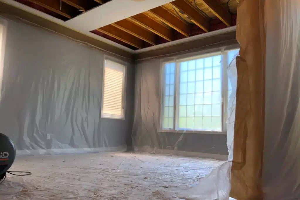 Comprehensive work-area protection with full room plastic covering during hydronic radiant heat piping system replacement.