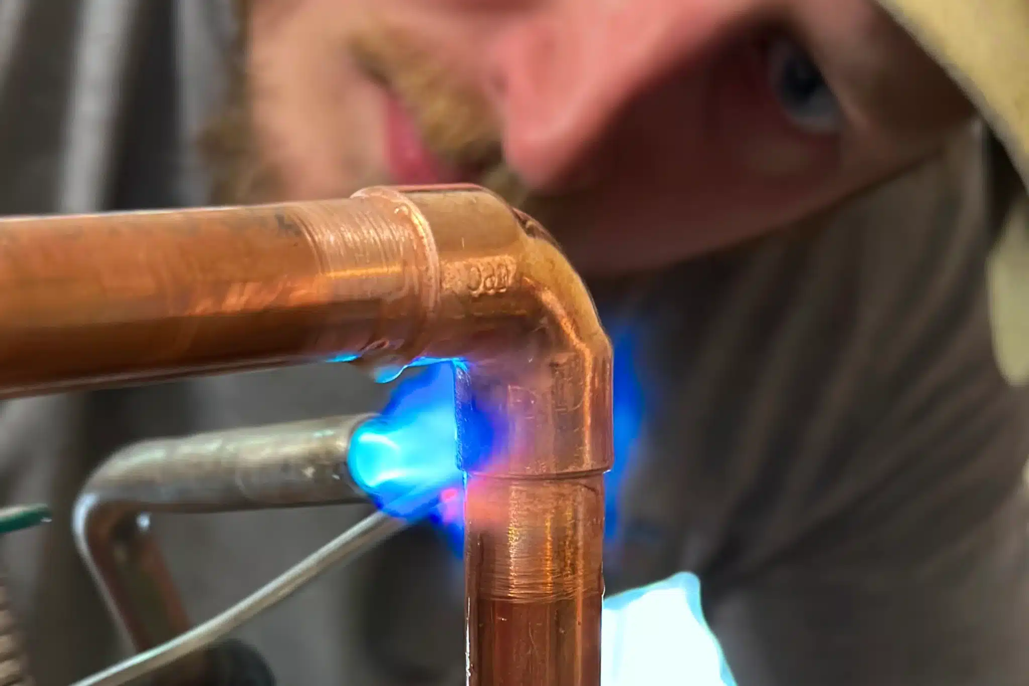 Replumb Specialties Inc. employee soldering copper pipe for shower valve installation in Colorado